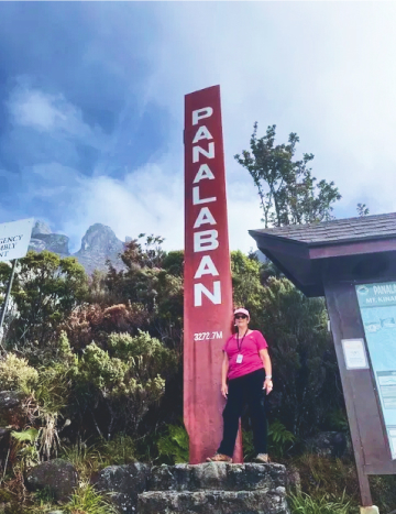 woman standing on a mountain in Borneo with a smile on her face.